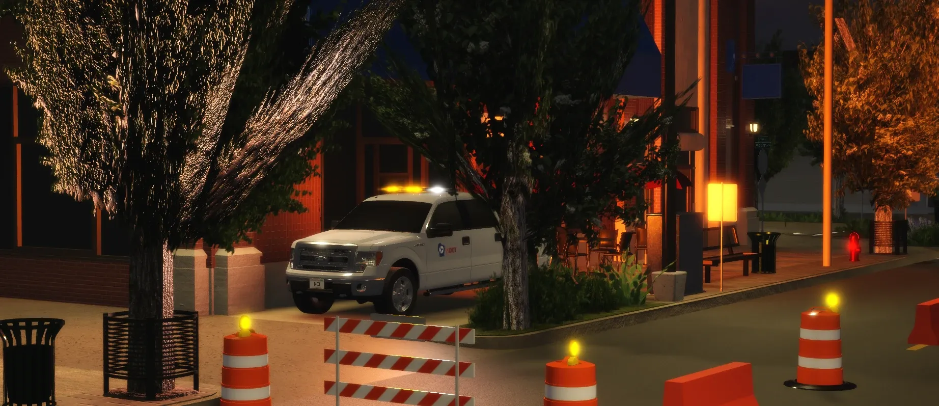 A white WisDOT pickup parked downtown at night behind flashing barrels and a striped barricade.